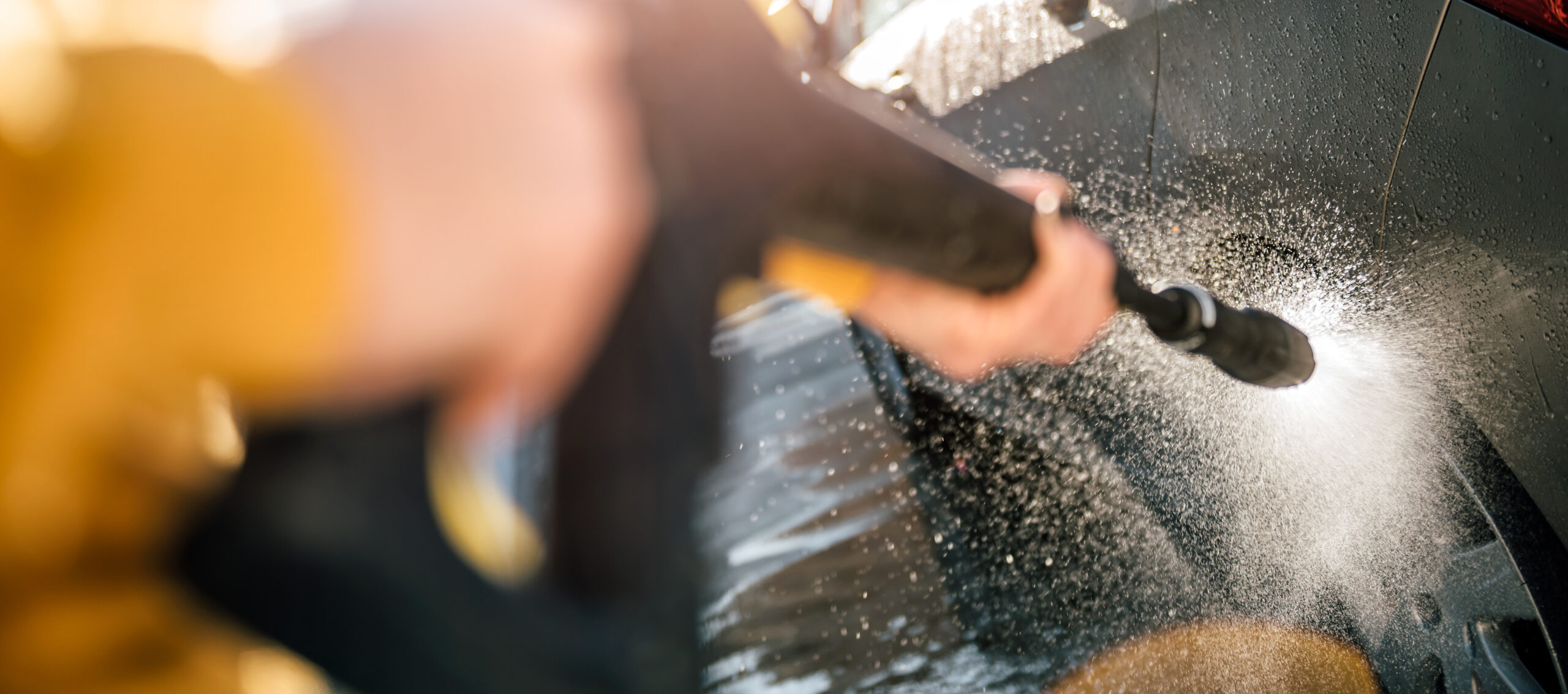 Woman washing her car with pressure washer at home backyard